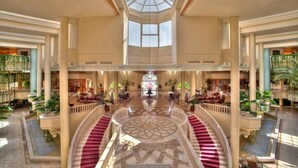 Eine prachtvolle Hotelhalle mit einer zentralen Treppe, hohen Decken und einem Oberlicht.