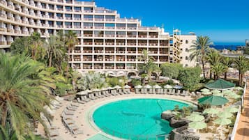 Relax by the resort's curved pool surrounded by sun loungers and umbrellas, with stunning views of the surrounding water.