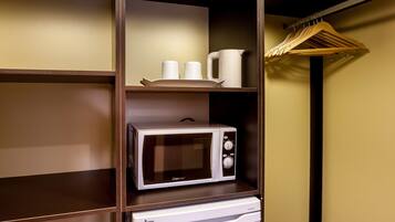 Une petite cuisine équipée d’un micro-ondes, d’un petit réfrigérateur et d’une étagère avec des tasses et un rouleau d’essuie-tout.