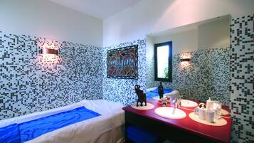 Ein Hotelzimmer mit einem Bett, einem roten Schminktisch mit Spiegel und einer Wand mit Mosaikfliesen.