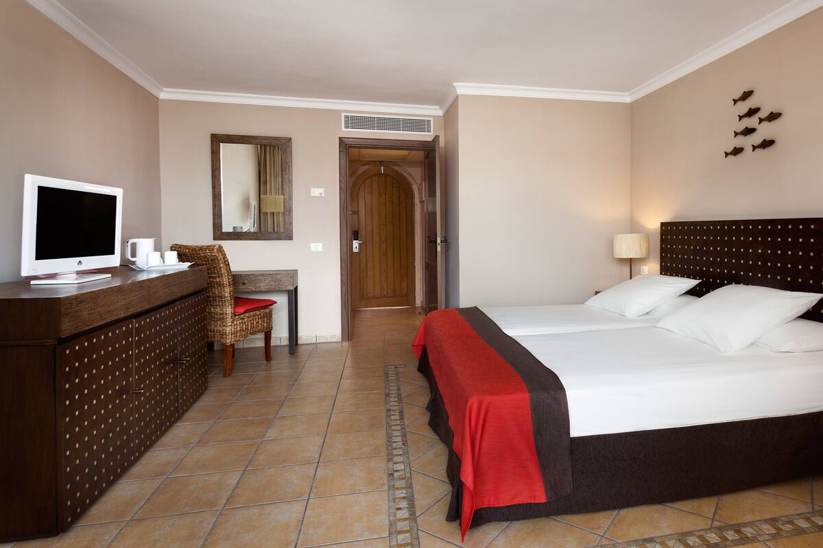 Une chambre d’hôtel équipée d’un lit, d’un bureau, d’une télévision et d’une chaise.
