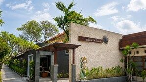Un bâtiment sur lequel on peut lire l’inscription « Bugan Villas », un espace extérieur abrité agrémenté de plantes et une statue.