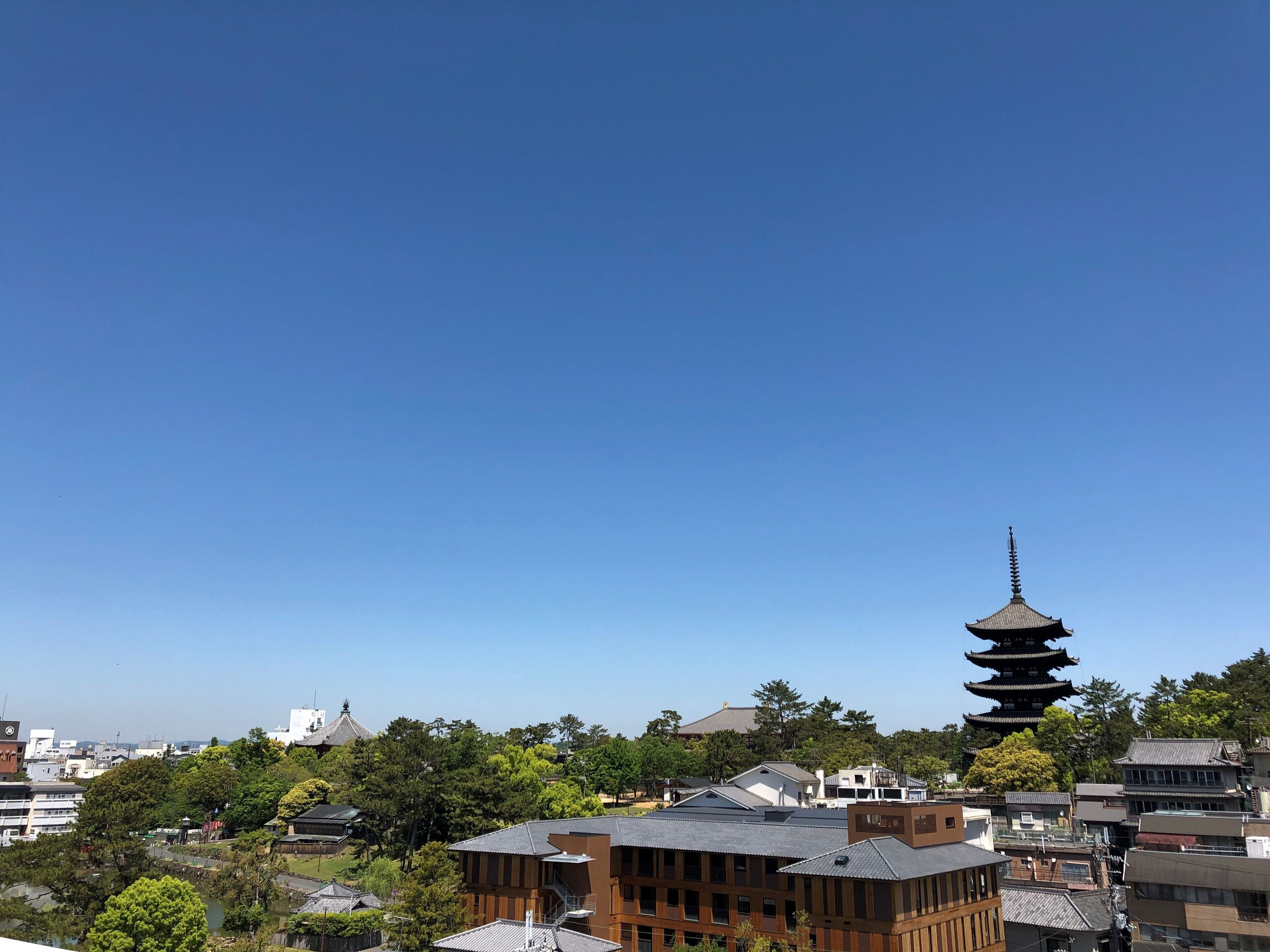 Una torre de estilo pagoda en medio de edificios urbanos, rodeada de vegetación y construcciones residenciales.
