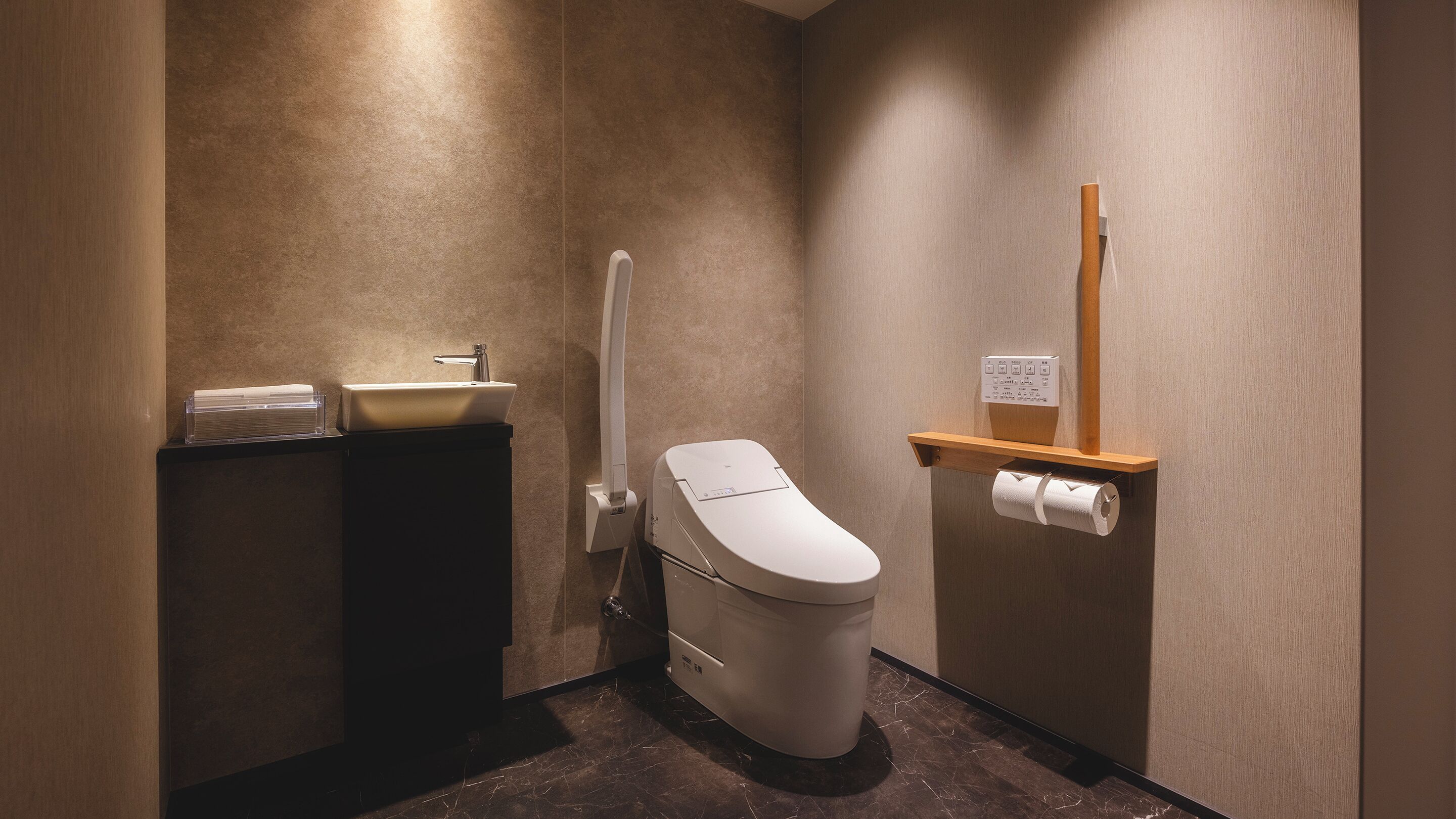 A modern bathroom with a toilet, sink, and hand dryer.