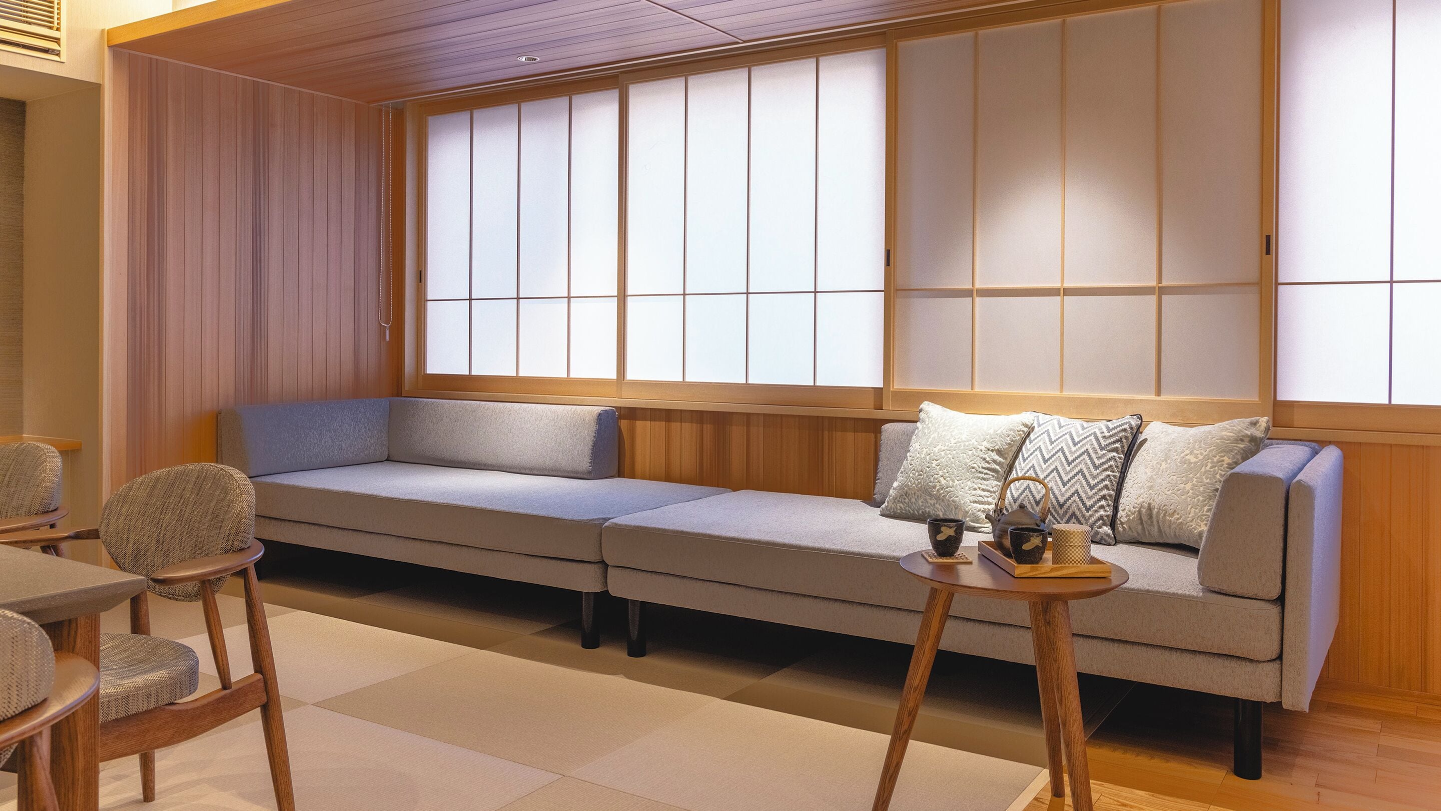 A traditional Japanese-style room with tatami flooring, a low wooden-framed sofa, and a shoji screen wall.