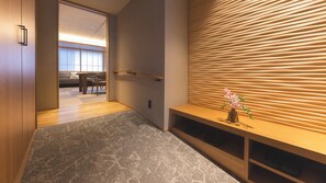 A modern interior with a wooden bench, a small table with a vase, and a room with a sliding door leading to a seating area.