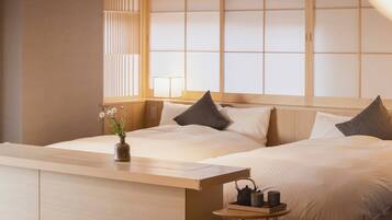 A hotel room with a bed, bedside table, and a small table with a teapot and cups.