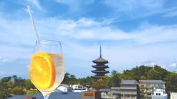A glass of water with an orange slice on a table with a view of a pagoda in the background.