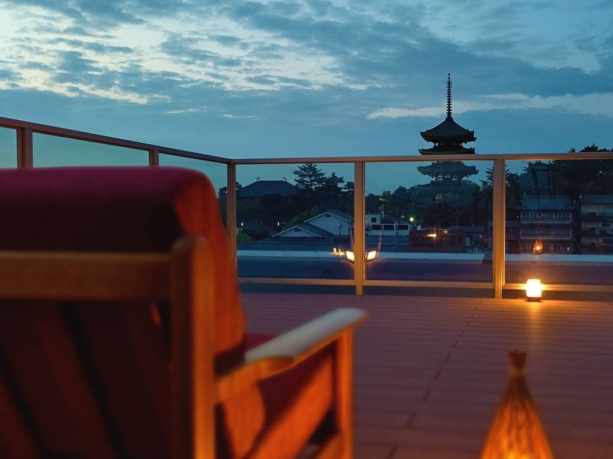 A wooden deck with a view of a pagoda and houses in the background.