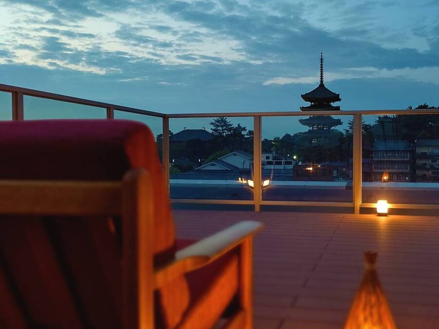 A wooden deck with a view of a pagoda and houses in the background.