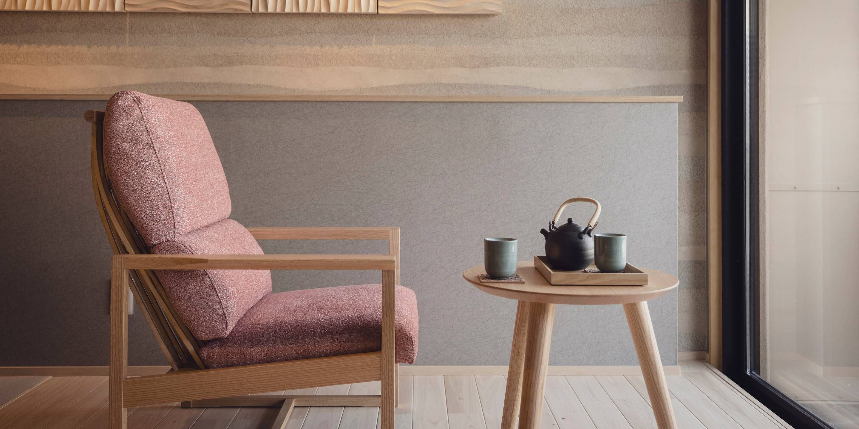 A modern room with a wooden chair and a small round table with a teapot and cups.