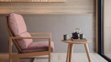 A modern room with a wooden chair and a small round table with a teapot and cups.
