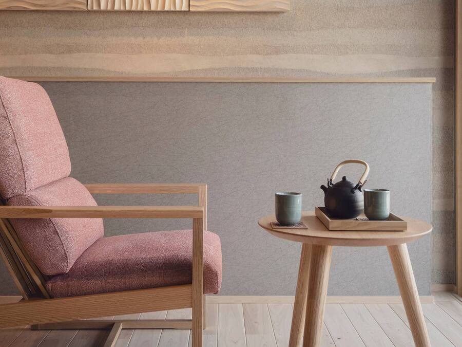 A modern room with a wooden chair and a small round table with a teapot and cups.