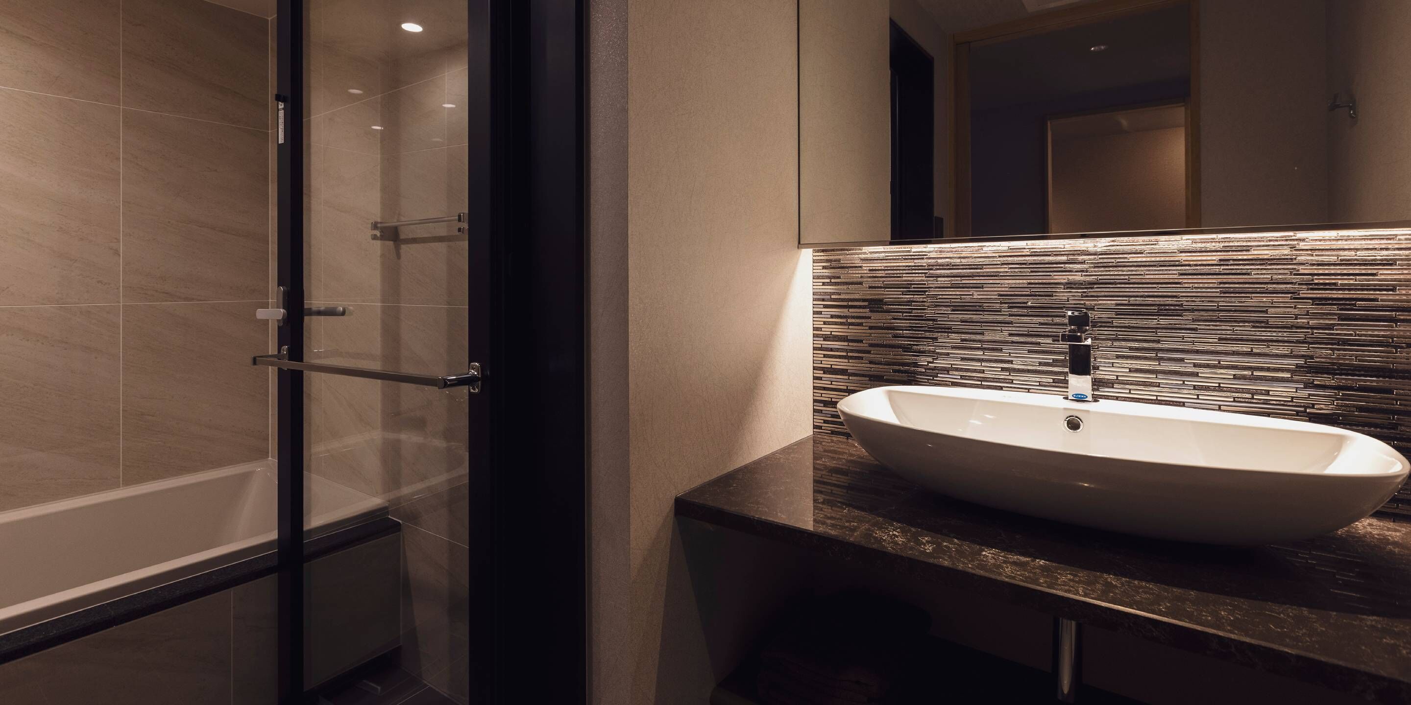 A modern bathroom with a glass-enclosed shower, a white sink, and a tiled backsplash.