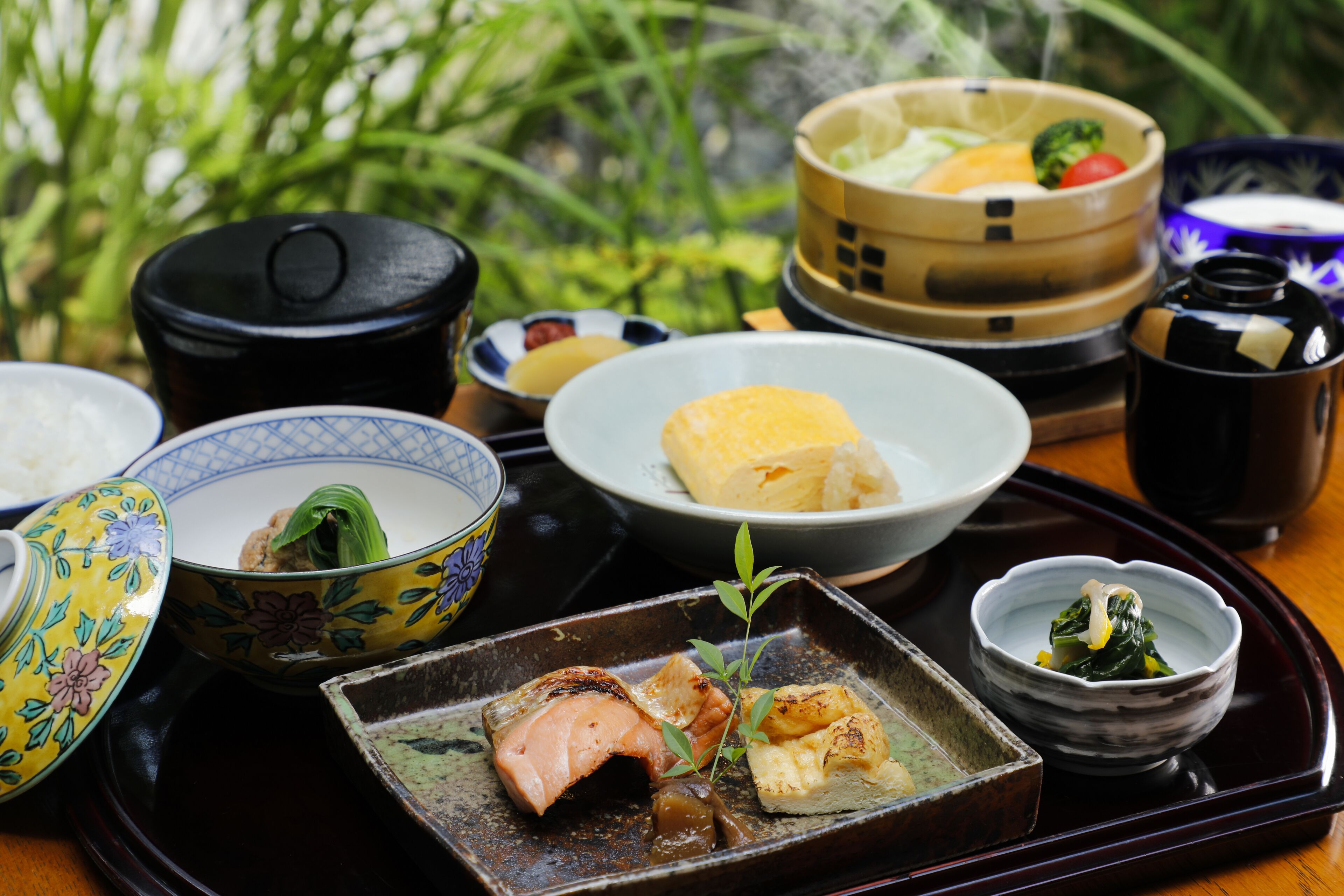 A tray with various dishes including a bowl of rice, a plate with a piece of meat, and several small bowls with different foods.
