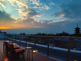 Terraza en la azotea con vista a una pagoda y al paisaje urbano al atardecer.