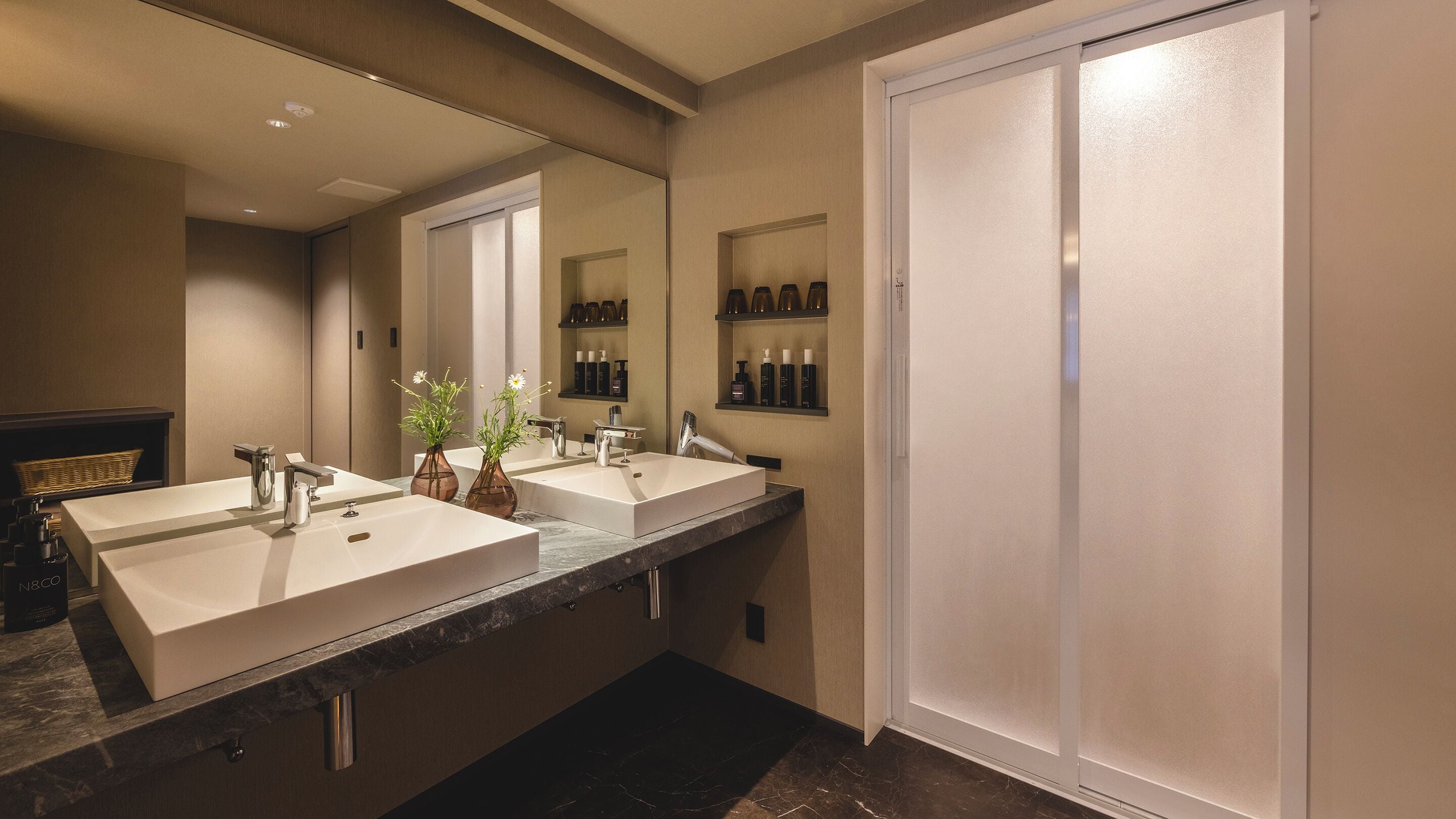 Une salle de bain moderne avec deux lavabos, un grand miroir et un dressing.