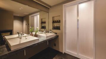 Une salle de bain moderne avec deux lavabos, un grand miroir et un dressing.