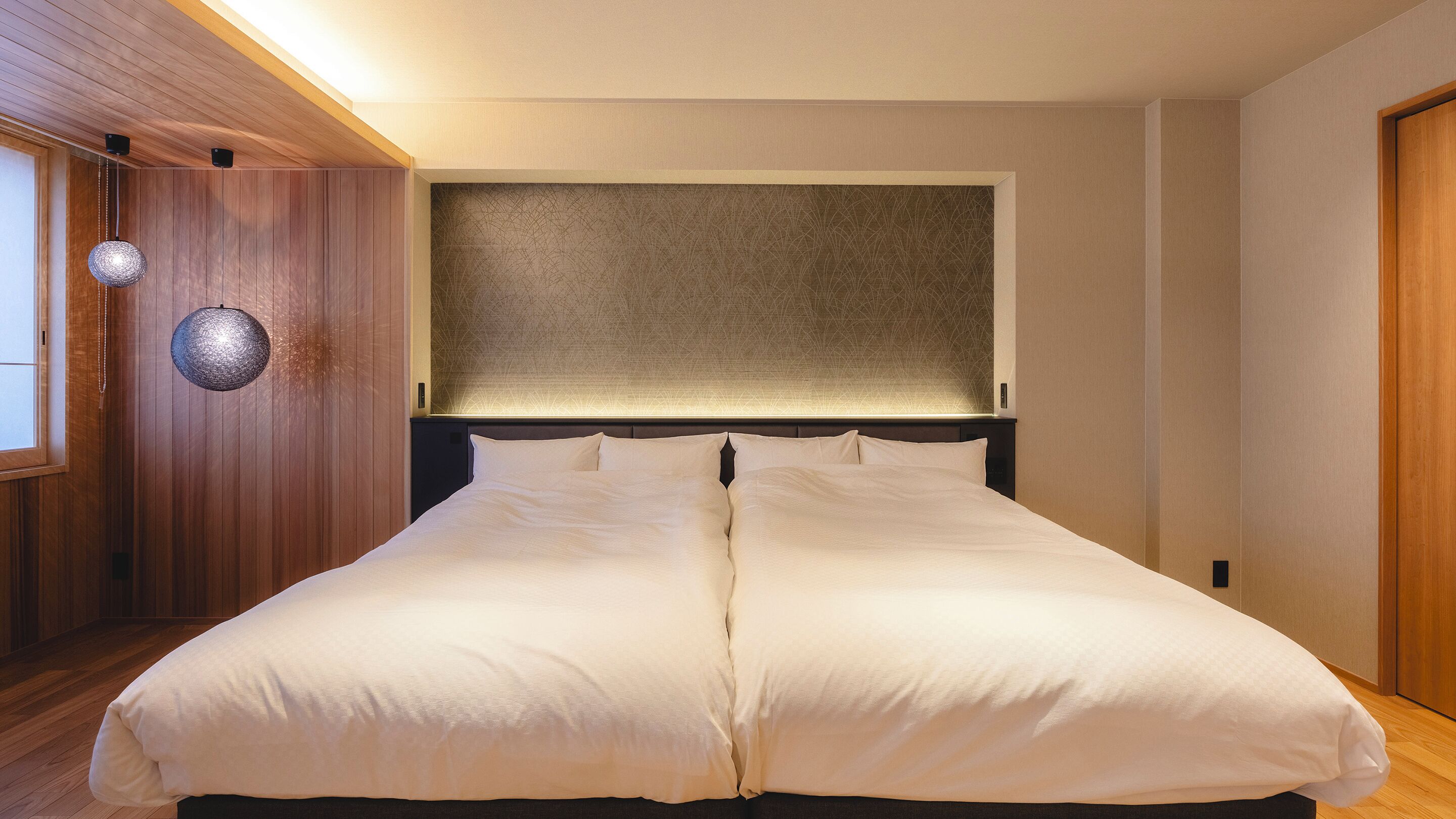 A double bed with a headboard, wooden panel walls, and a textured wall behind the bed.
