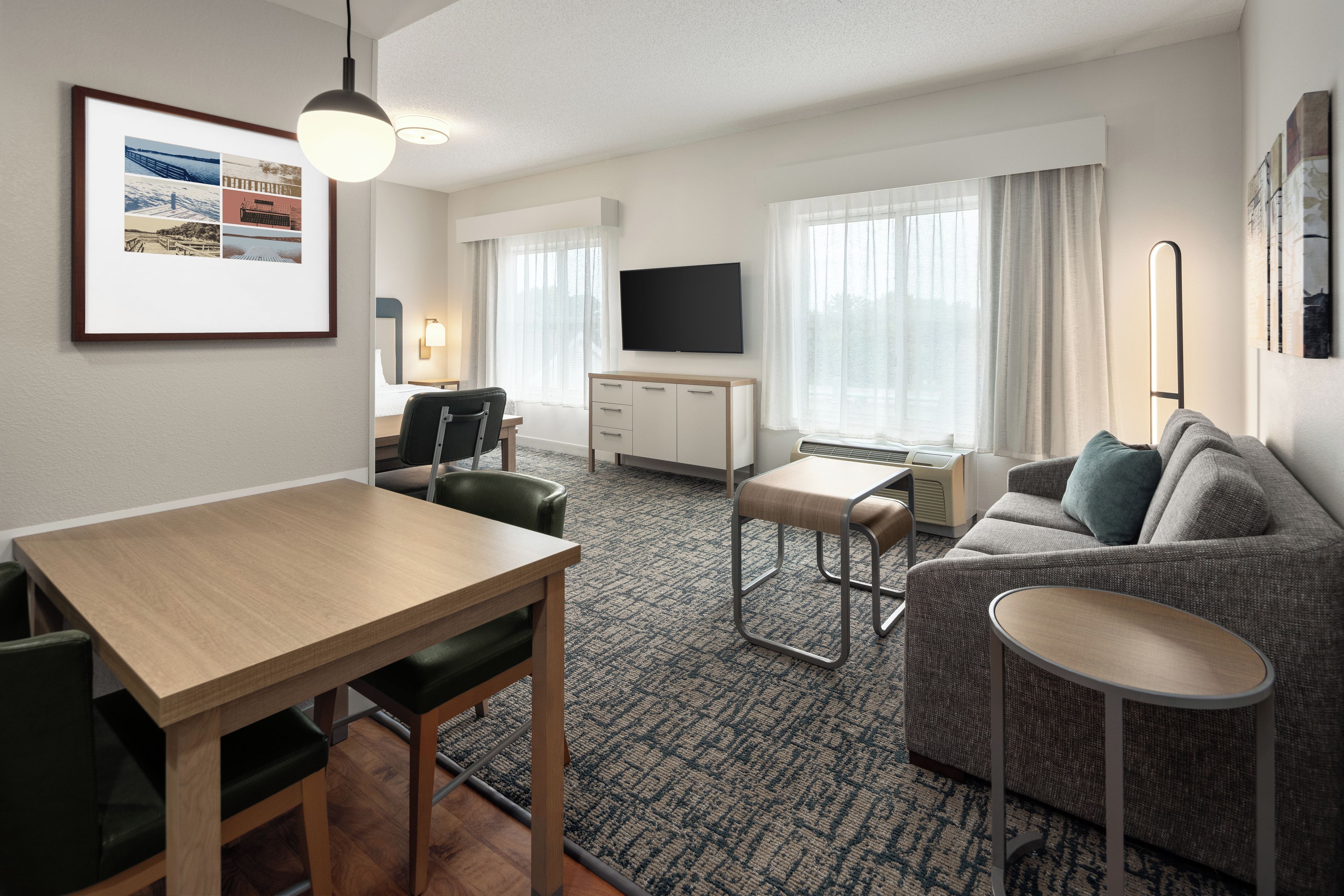 Una habitación de hotel con una mesa de comedor, un sofá, un televisor y una mesita.