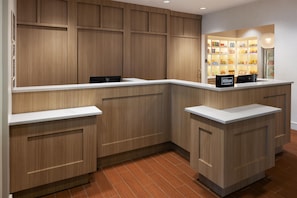 A hotel reception area with wooden paneling, a counter, and a minibar. - Homewood Suites by Hilton St Louis Park at West End (St. Louis Park)