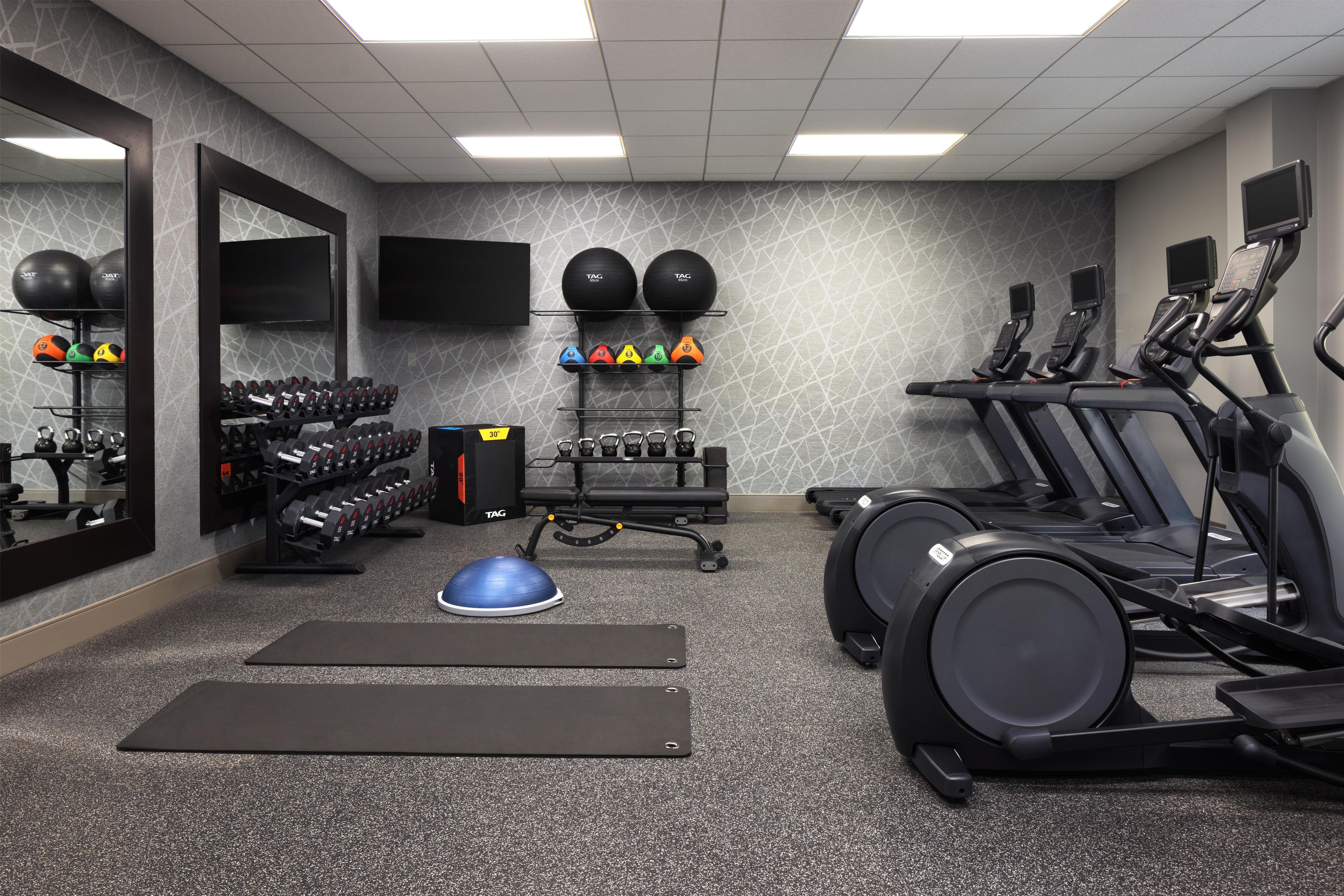 A gym with exercise equipment, including treadmills, weight machines, and a variety of weights.