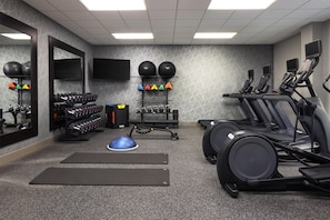 A gym with exercise equipment, including treadmills, weight machines, and a variety of weights.