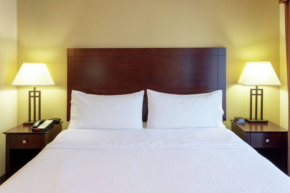 A hotel room with a large bed, two bedside tables with lamps, and a telephone on one of the tables.