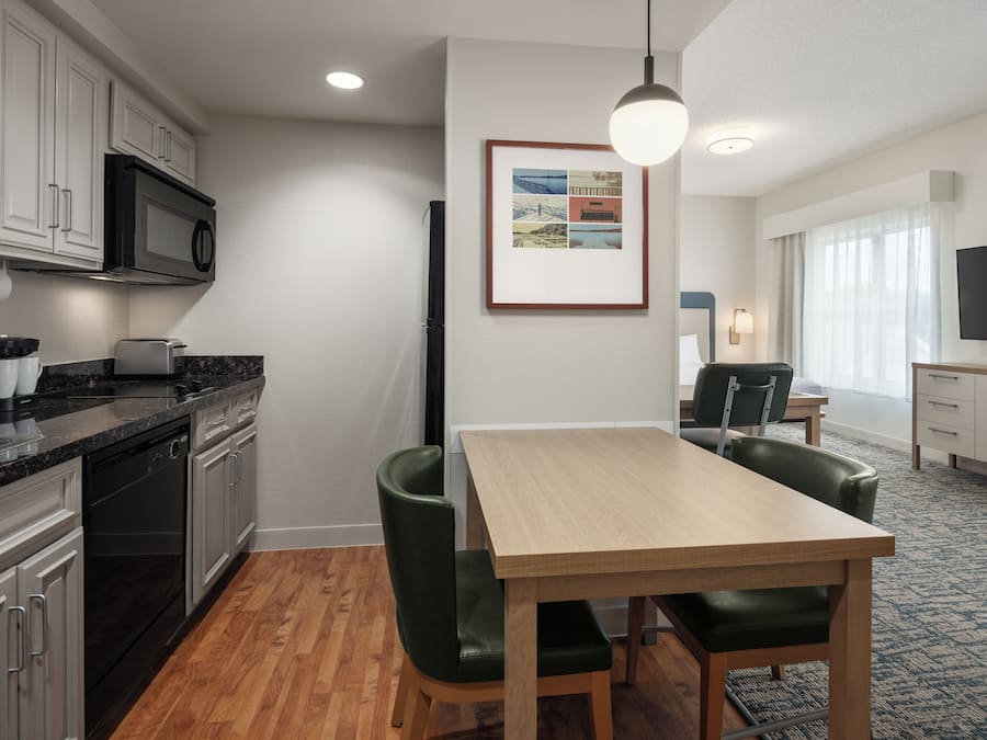 A modern kitchen with a dining area, wooden table, and chairs.