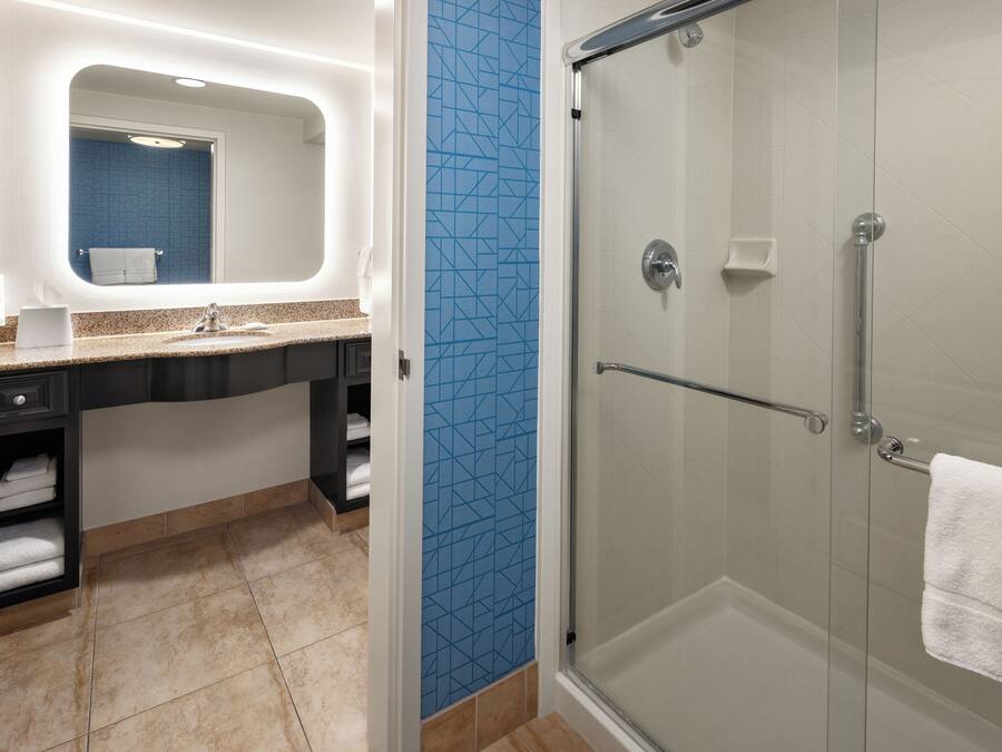 Une salle de bain avec une douche à parois de verre, un lavabo avec une serviette et un miroir.