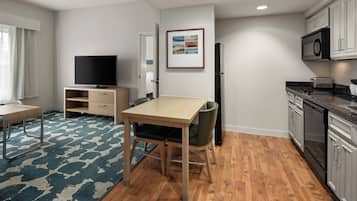 A modern kitchen with wooden cabinets, a built-in microwave, and a dining area with a table and chairs.