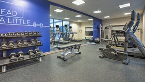 Un gimnasio con equipo de ejercicio, incluyendo mancuernas, cintas de correr y una bicicleta estática.