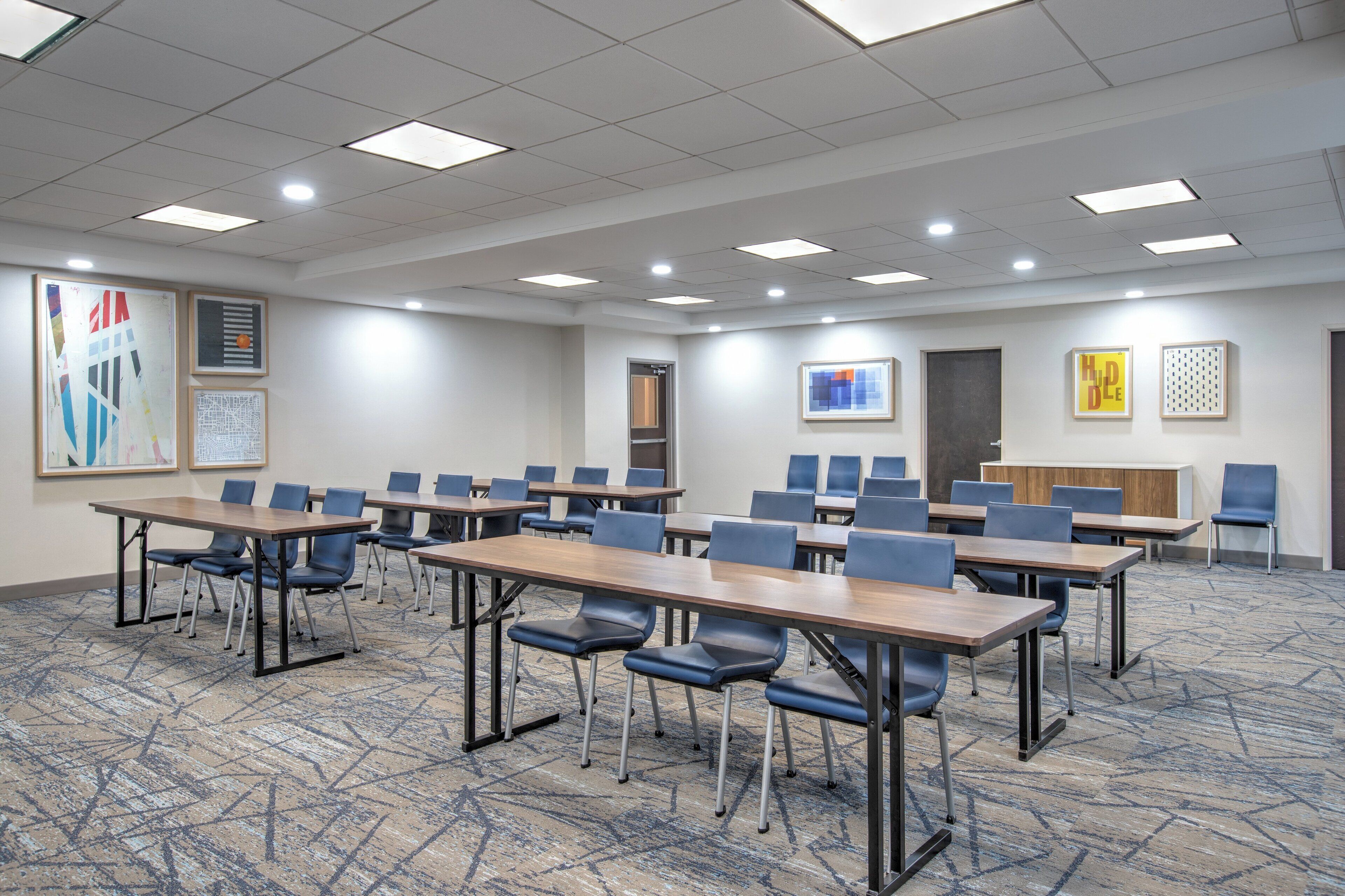 Une salle de conférence dotée de plusieurs tables et de nombreuses chaises, disposées en rangées.