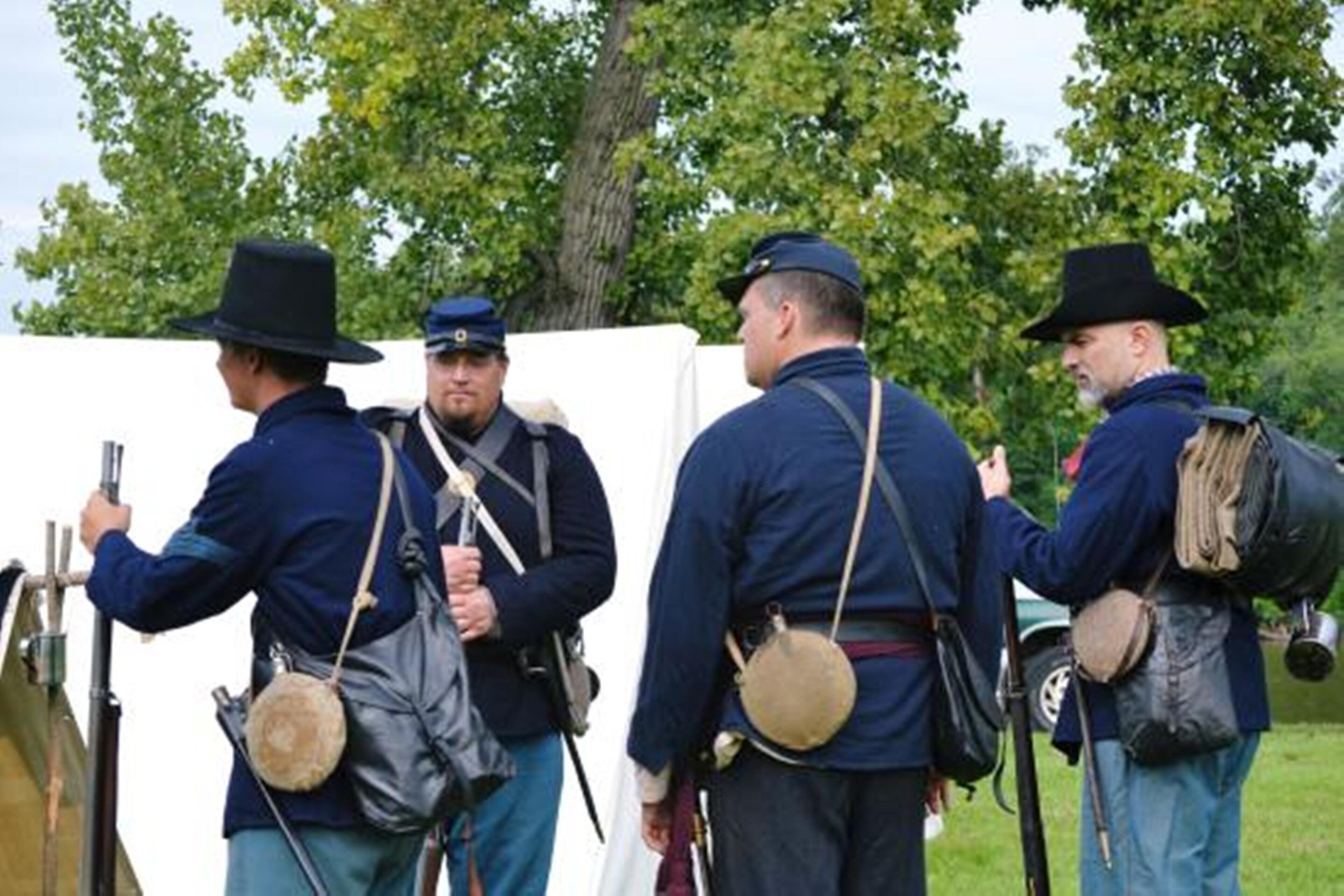 Een groep mensen in historische militaire uniformen staat buiten.