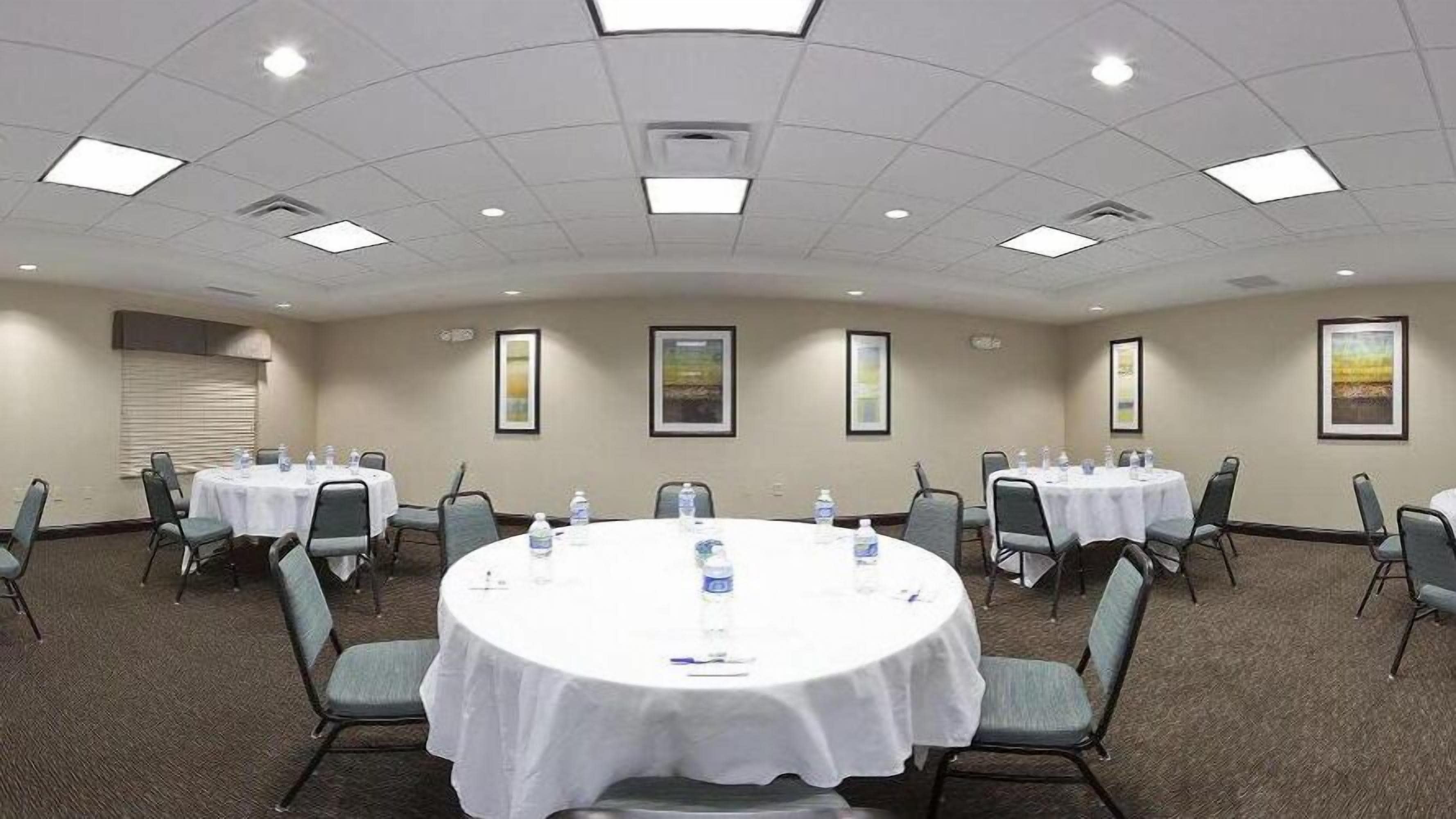 A conference room with round tables, chairs, and framed pictures on the walls.