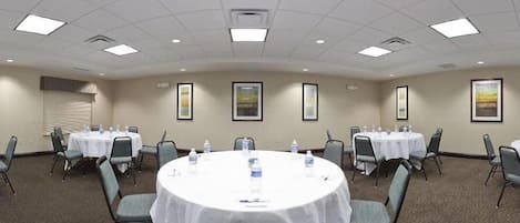 A conference room with round tables, chairs, and framed pictures on the walls.