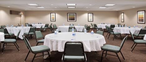 A conference room with round tables, chairs, and water bottles.