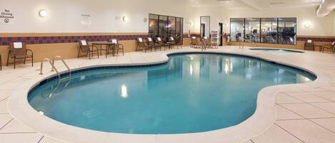 An indoor swimming pool with a tiled floor, lounge chairs, and a no diving sign.