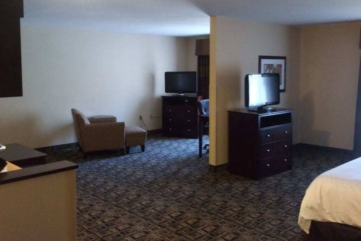 Ett hotellrum med en säng, ett skrivbord, en stol, en tv och en byrå.