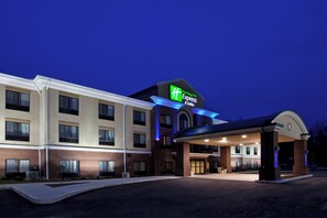A Holiday Inn Express & Suites building with a brick facade, multiple windows, and a covered entrance.