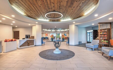 A spacious lobby with a central round table, seating area, and a reception desk.