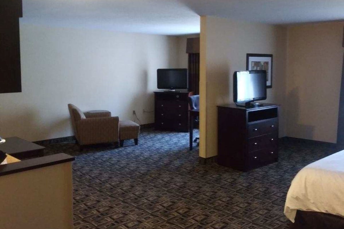 A hotel room with a bed, a desk, a chair, a television, and a dresser.
