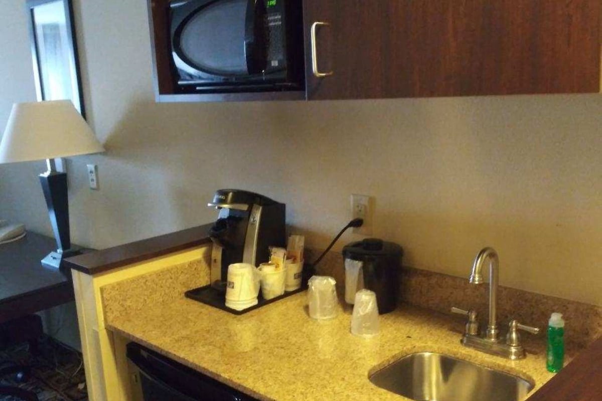 A compact kitchenette with a microwave, coffee maker, and sink.