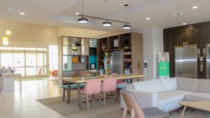 A modern interior with a dining area, a sofa, and a refrigerator. - Holiday Inn Yakima by IHG (Yakima)