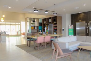A modern interior with a dining area, a sofa, and a refrigerator. - Holiday Inn Yakima by IHG (Yakima)