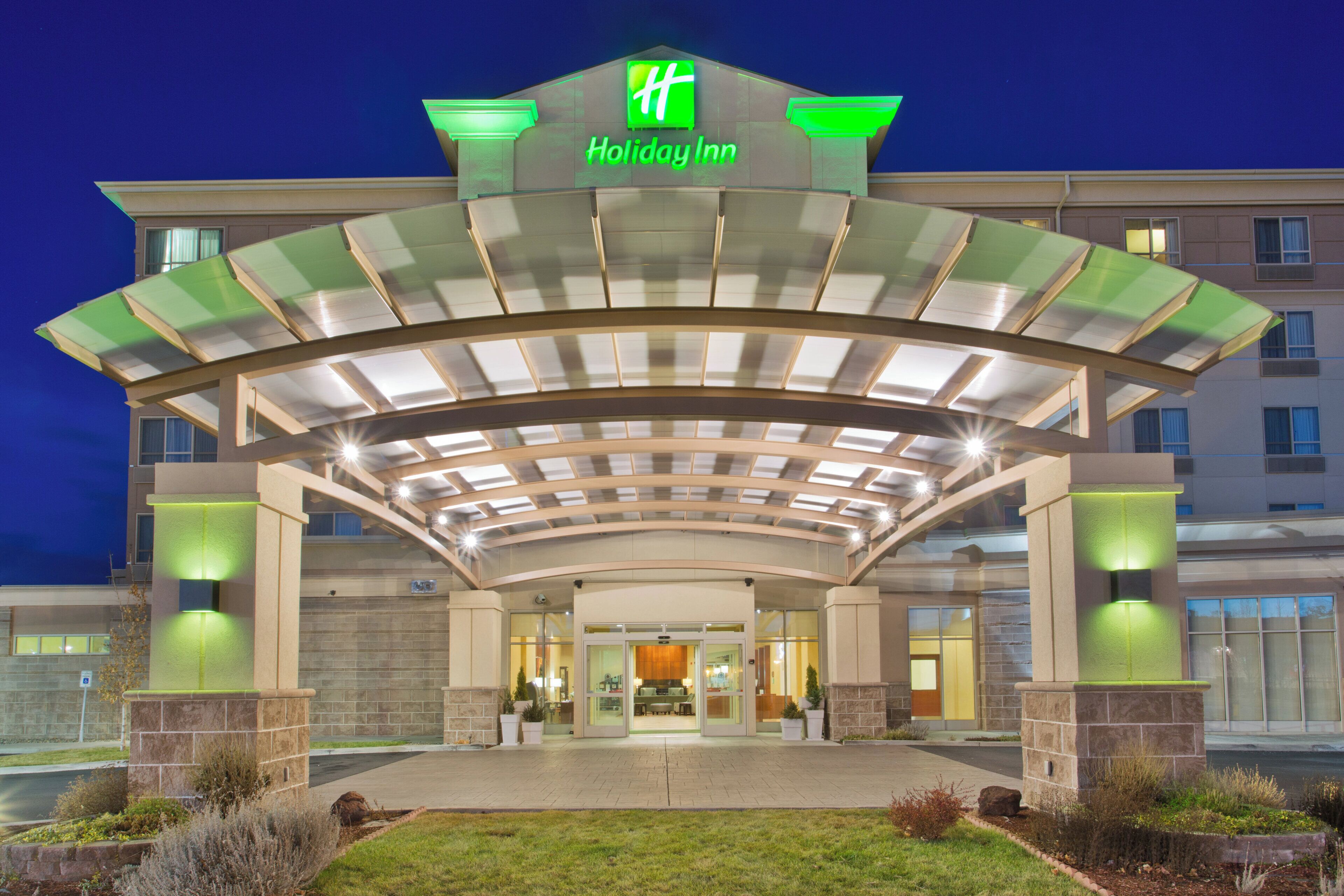L’entrée d’un hôtel Holiday Inn, avec un passage couvert, des portes en verre et une pelouse aménagée.