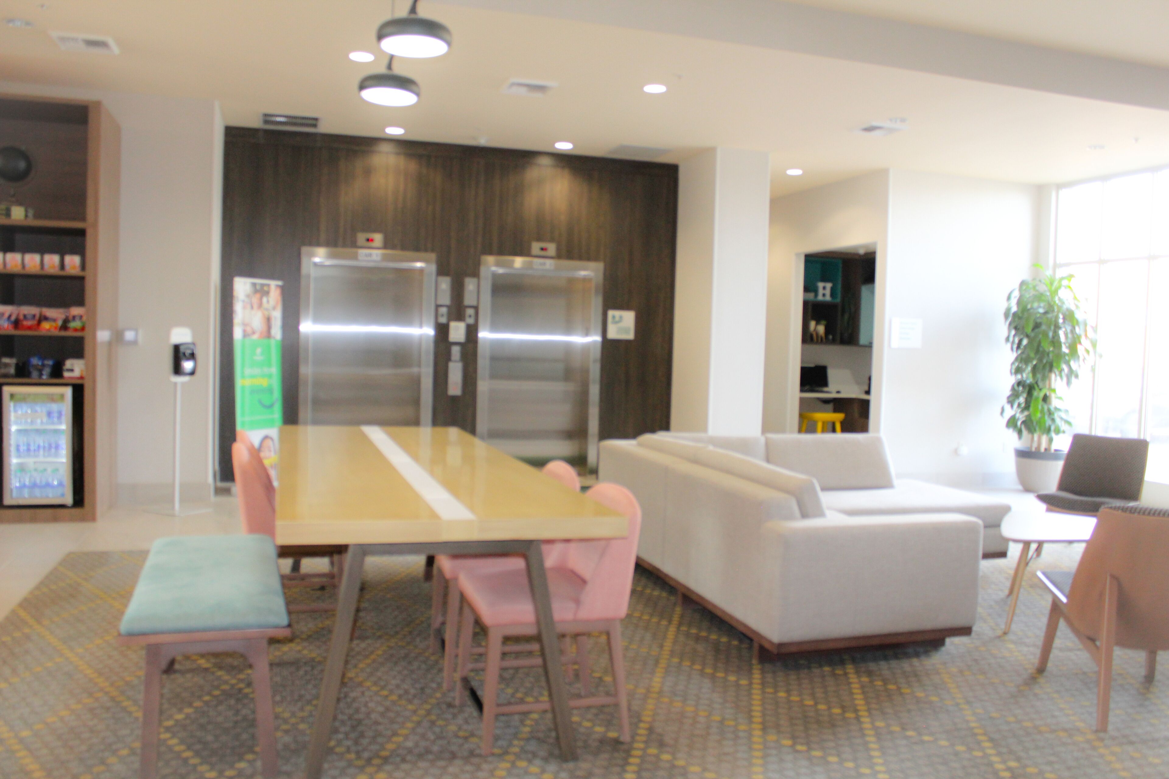 A modern interior with a dining area, sofas, and a refrigerator.
