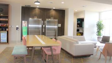 A modern interior with a dining area, sofas, and a refrigerator.