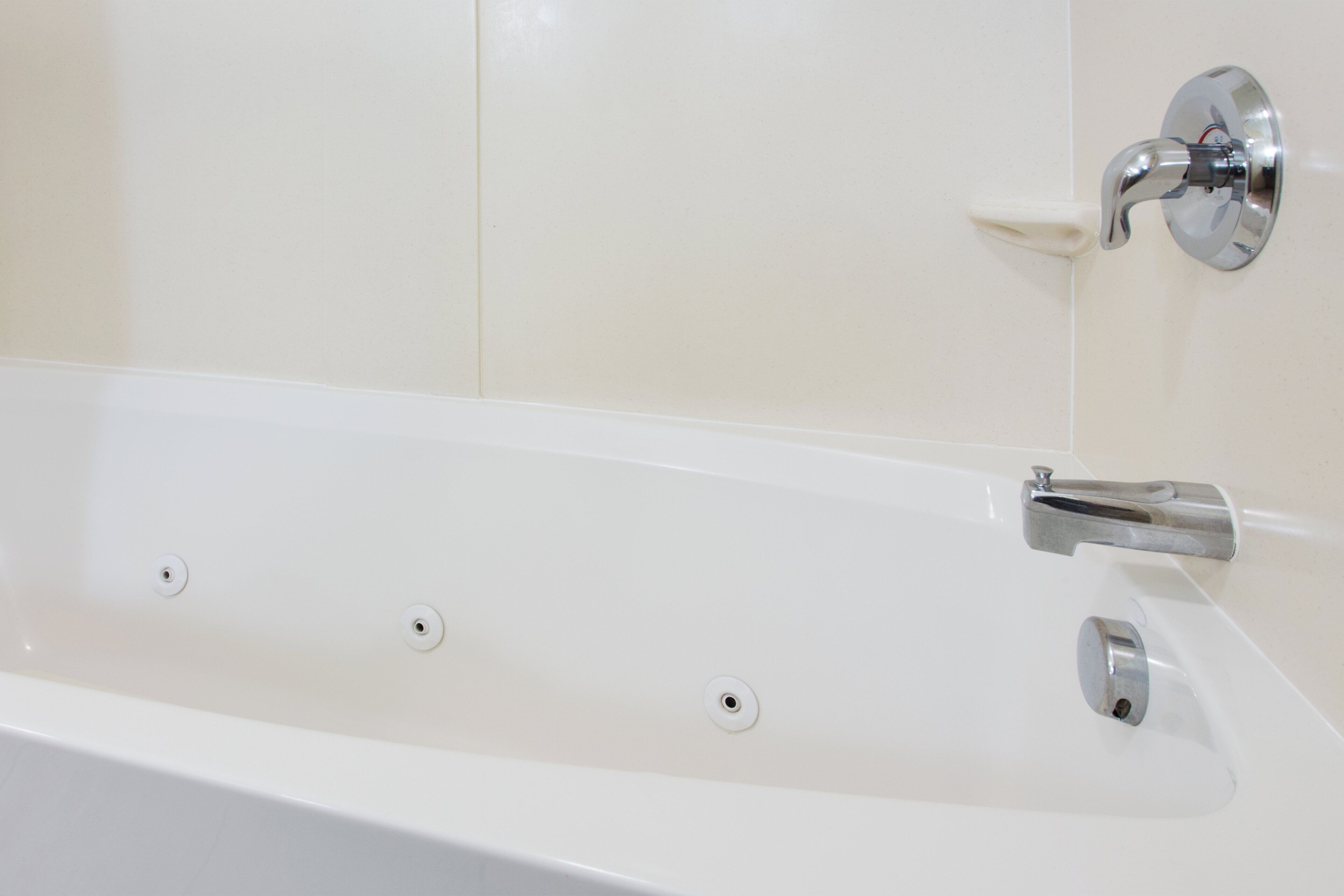 A white bathtub with a chrome faucet and a single drain.