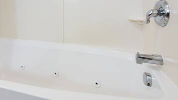 A white bathtub with a chrome faucet and a single drain.